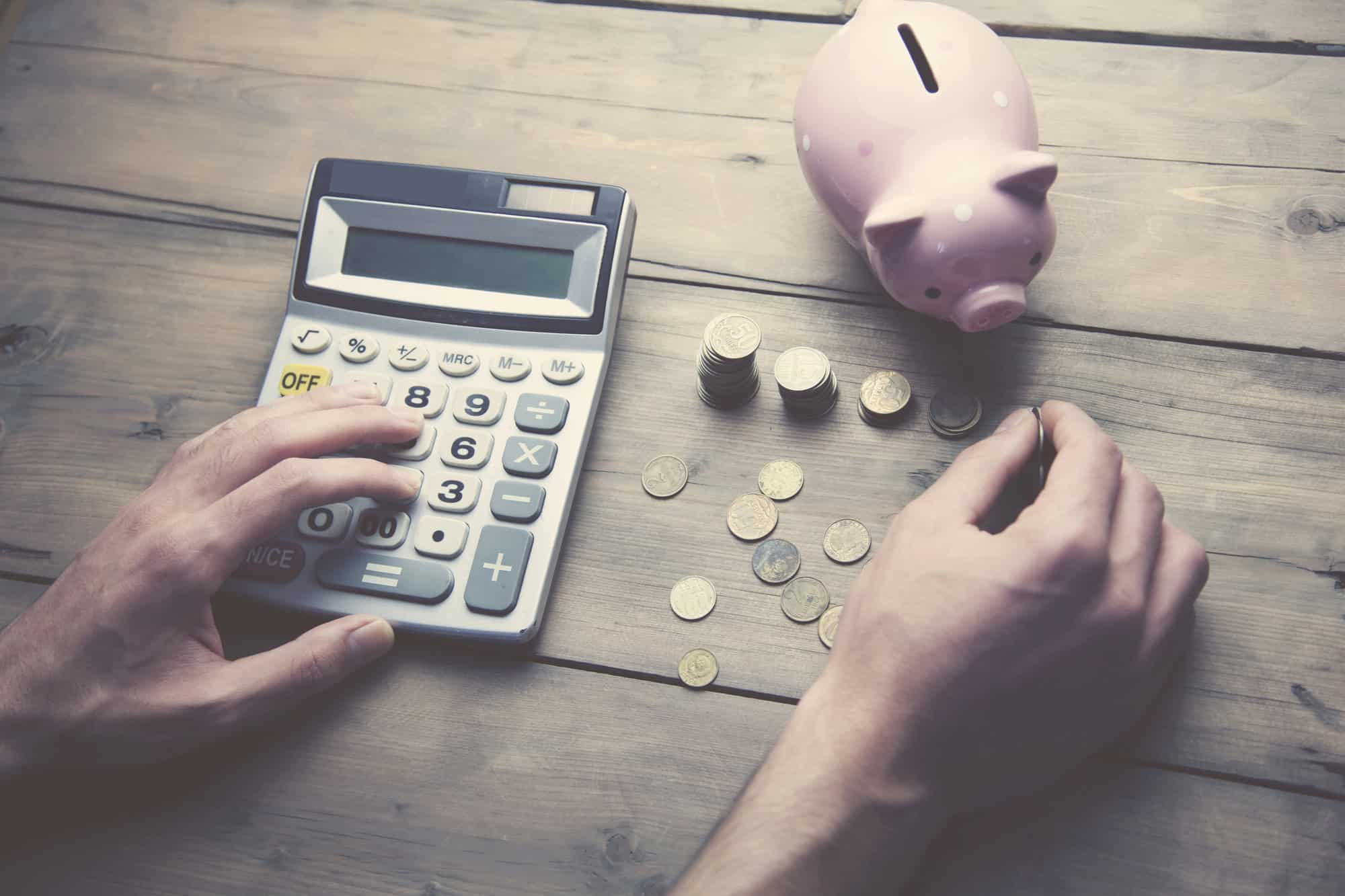 counting coins on a table with a calculator