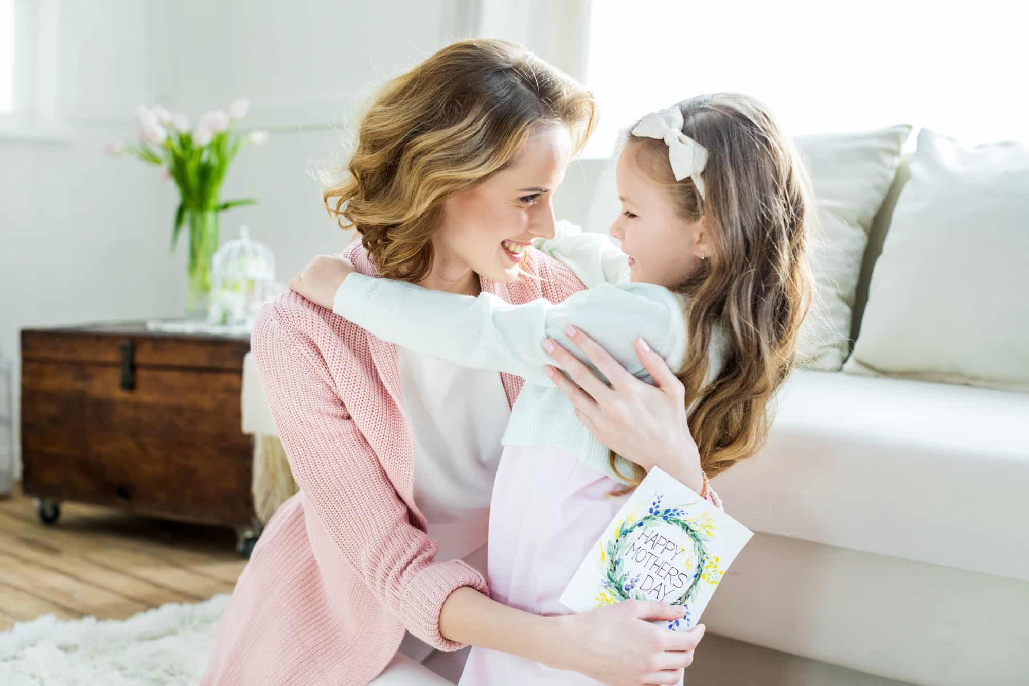 mom holding daughter in her lap inside home