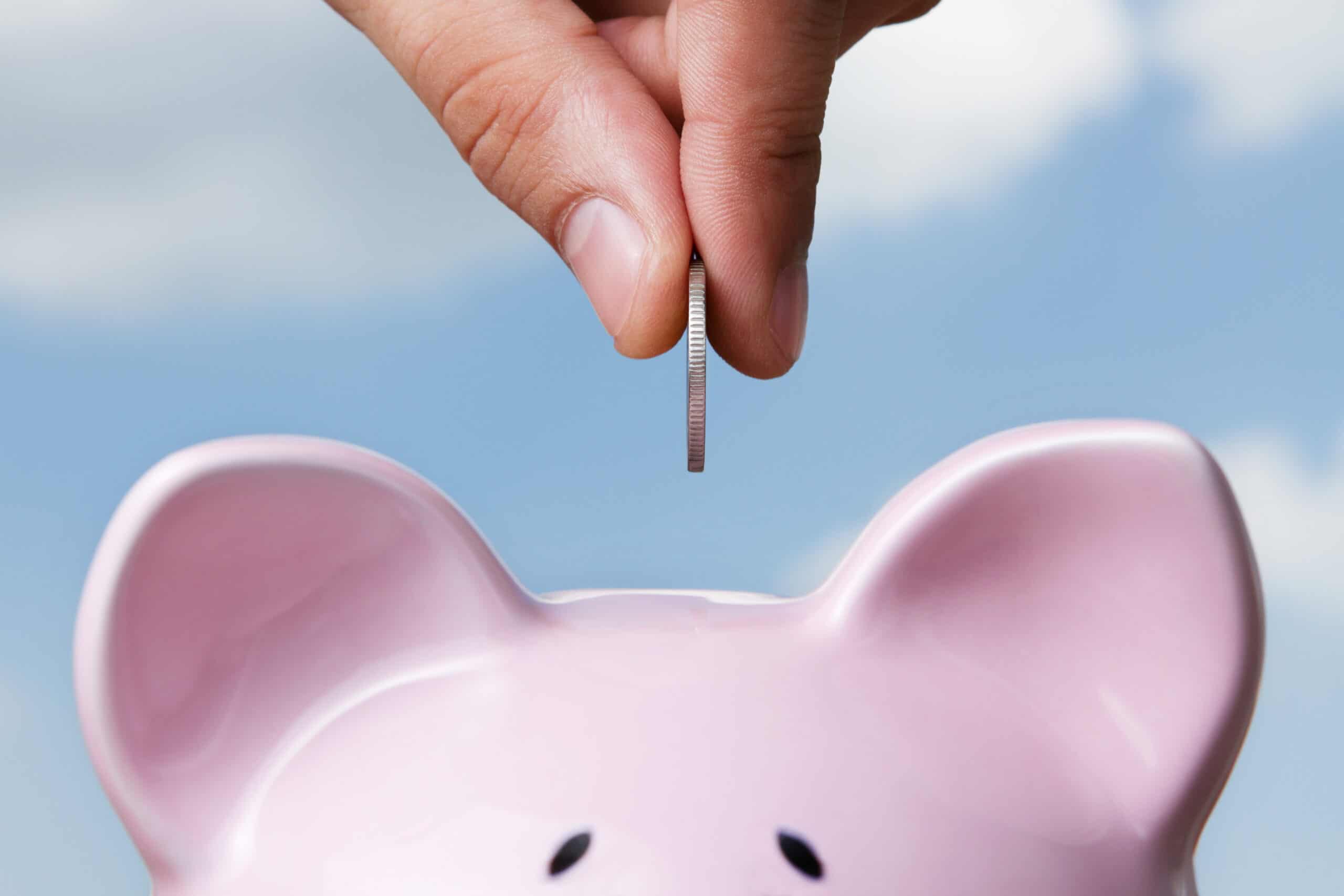money being put into the top of a piggy bank