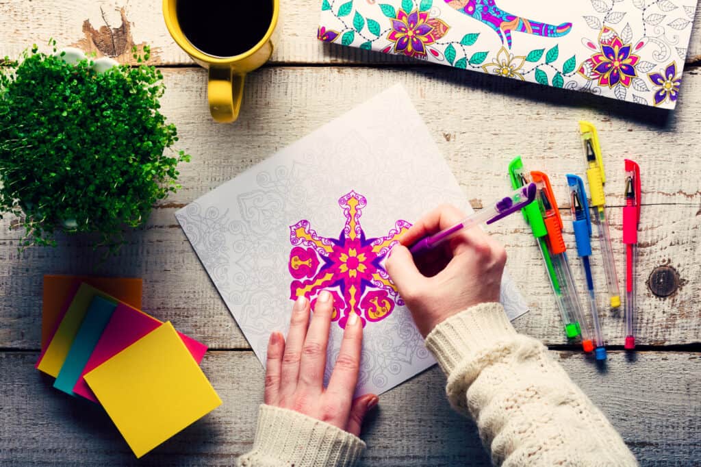 Woman coloring an adult coloring book, new stress relieving trend, mindfulness concept, hand detail
