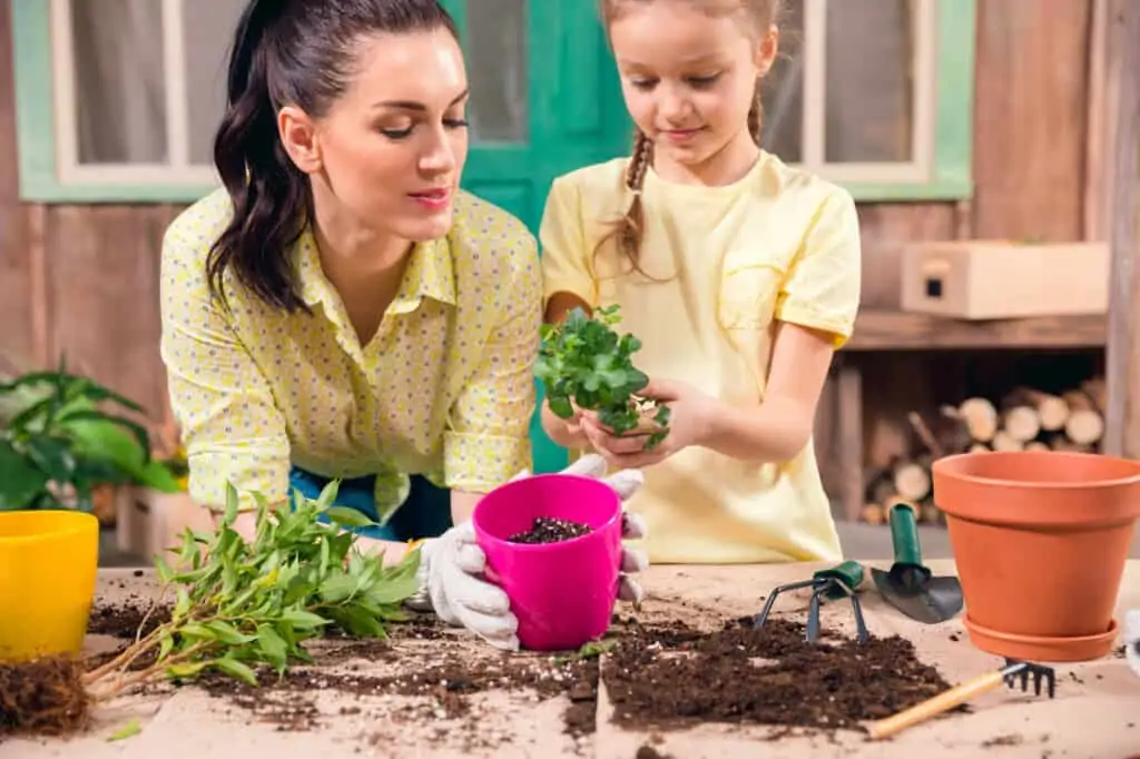 mom and daughter planting plants in planters