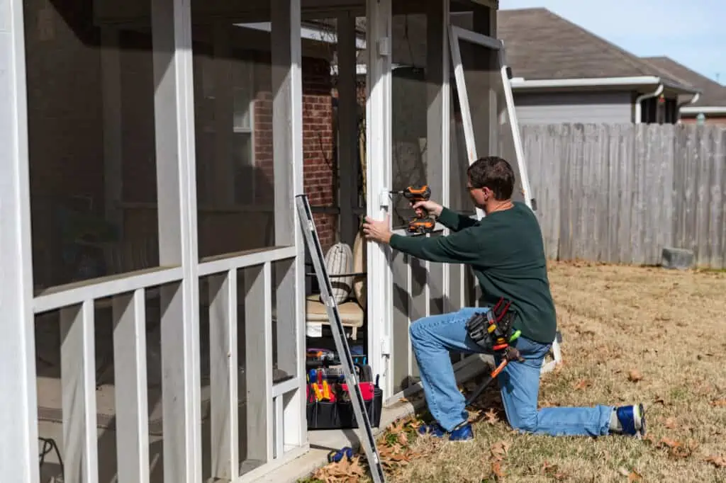 Homeowner works on repairing door to screened in back porch