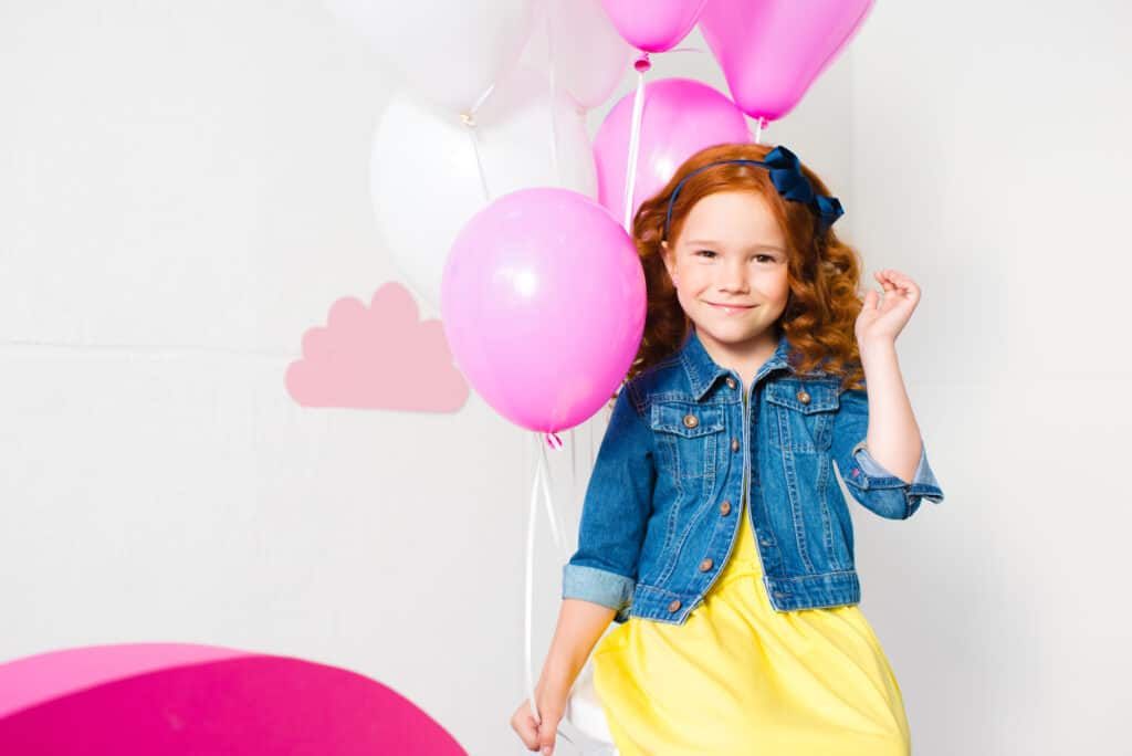 little girl holding a pink baloon
