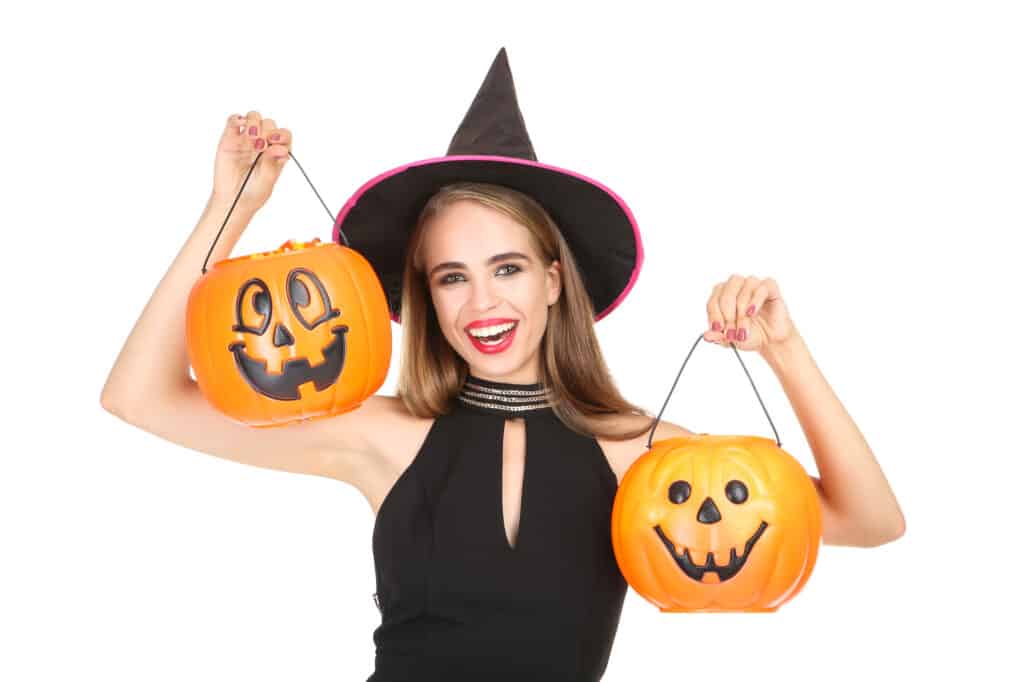 Beautiful woman in black costume holding halloween pumpkin buckets on white background