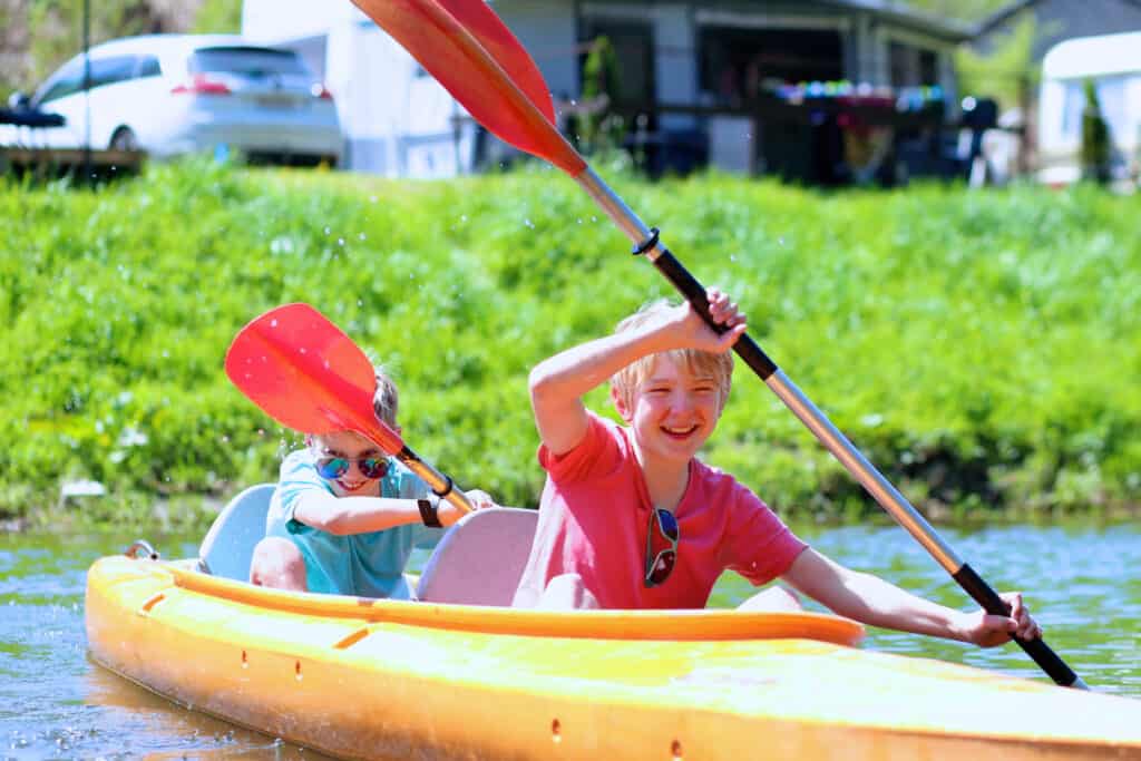 Two boys kayaking on the river. Active happy friends, teenage schoolboys, having fun together enjoying adventurous experience with kayak on a sunny day during summer vacation
