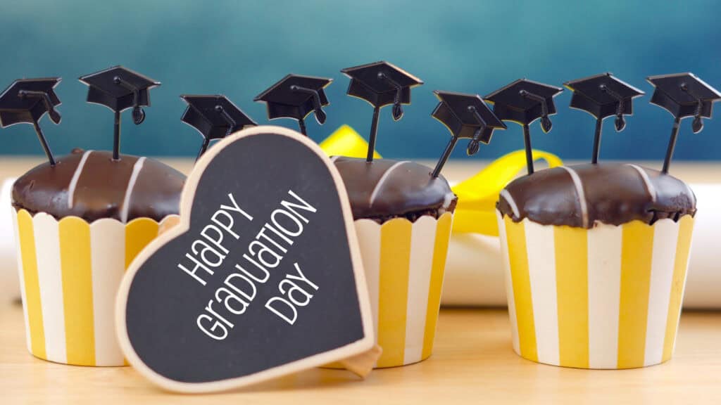 Yellow and blue theme graduation party cupcakes with cap hats toppers and decorations.