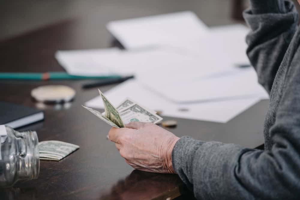 man counting dollars bills at a desk