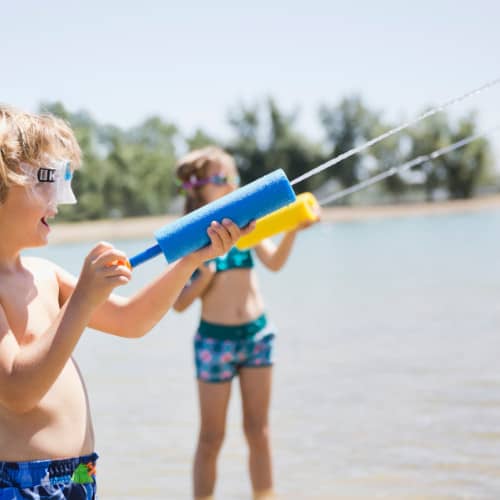 Kids using super soakers to shoot water