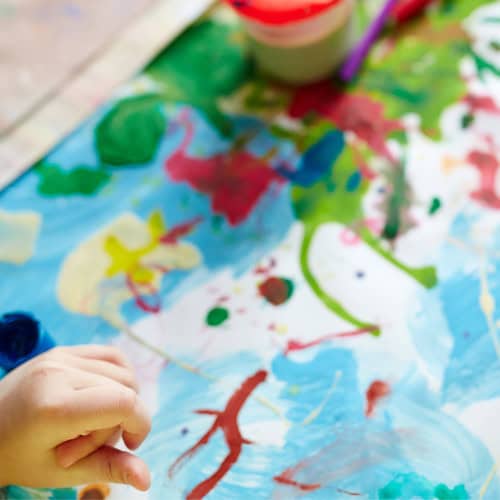 hand of a child in front of a painting